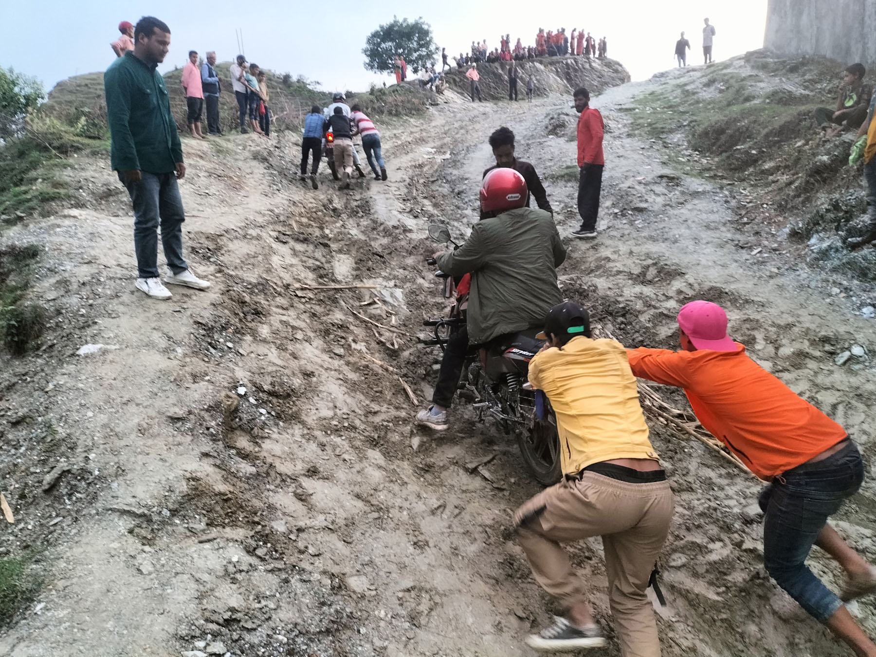 फसेको मोटरसाइकल धकेलेर निकाल्दै