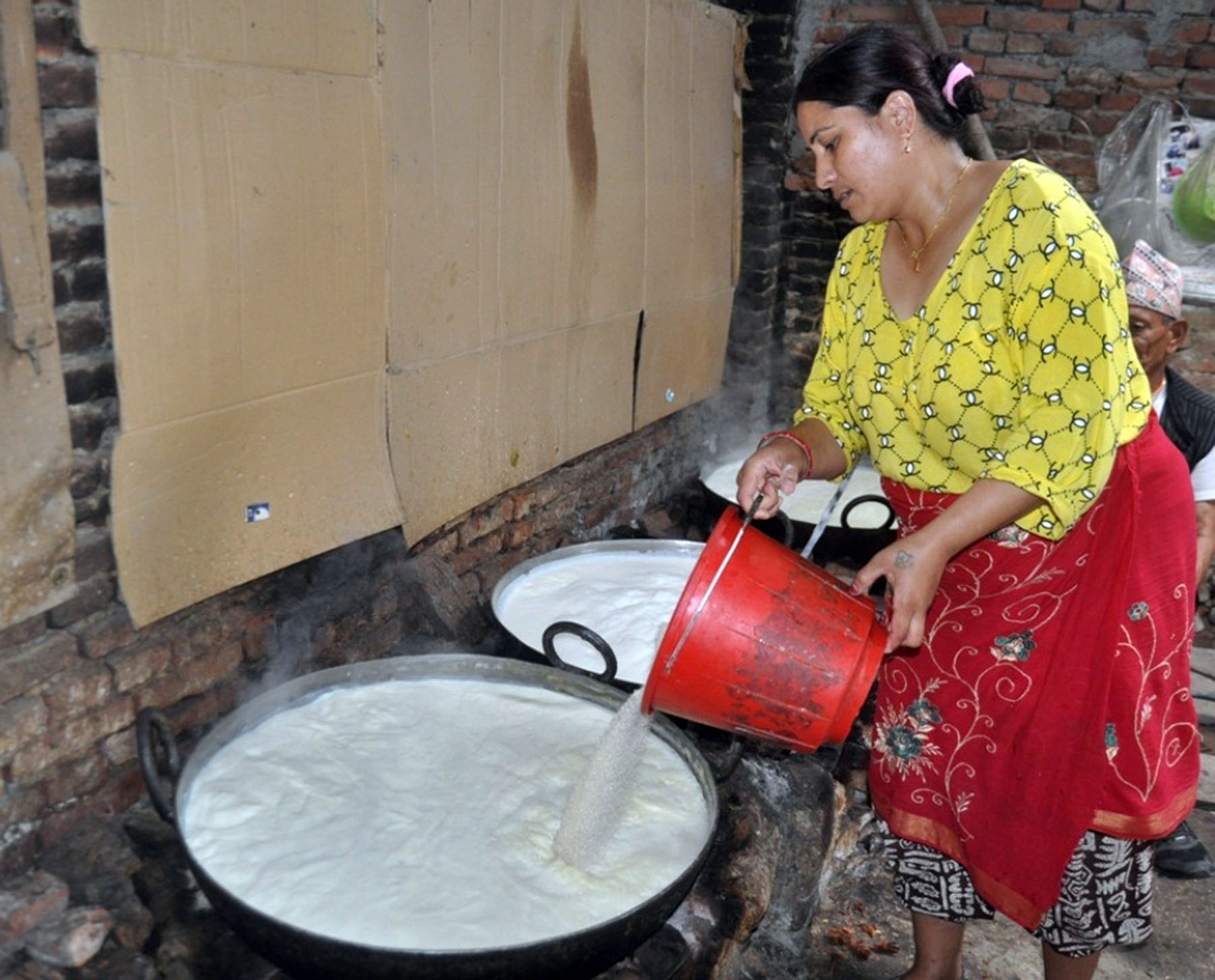 दही बनाउन दूध उमाल्दै महिला