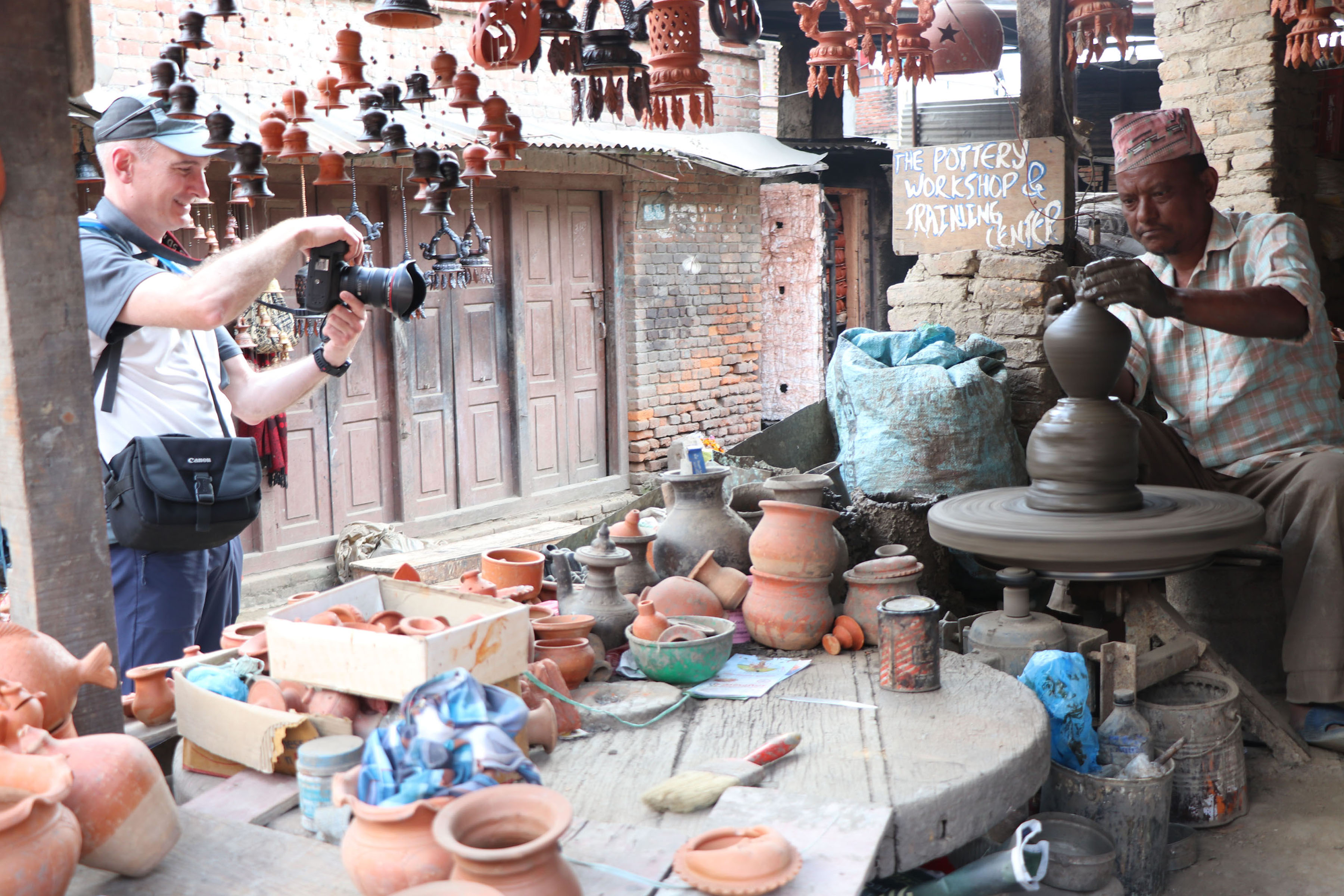 बनाउँदै गरेको माटोको भाँडाको तस्बिर लिँदै पर्यटक