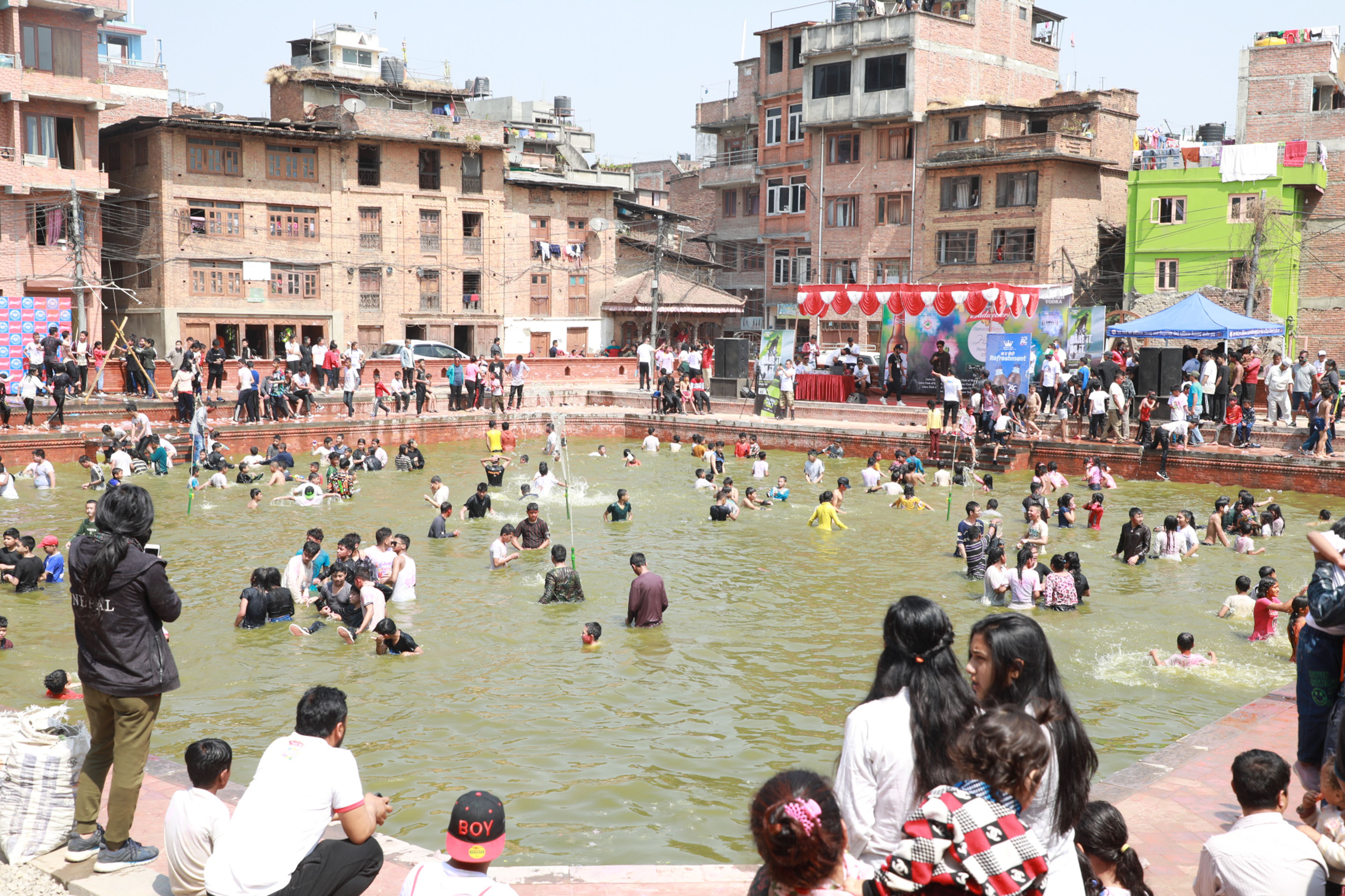पोखरीको पानीमा खेल्दै बालबालिका तथा युवा